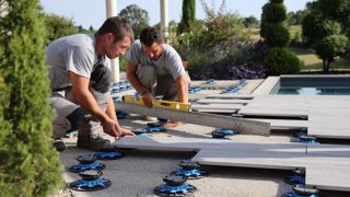 Pose de dallages en grès cérame par des ouvriers paysagistes travaillant au sein du réseau Daniel Moquet.