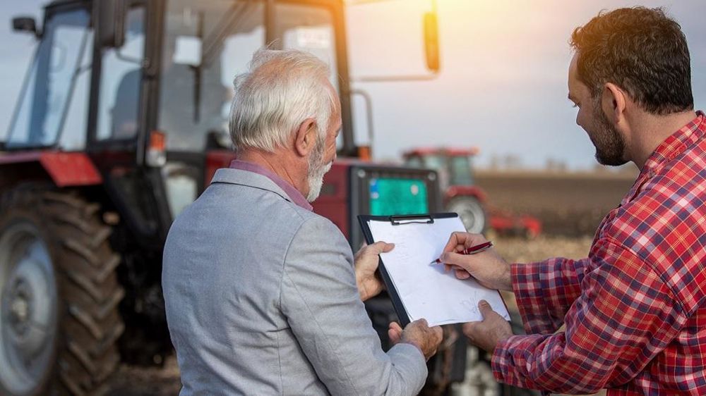 Agriculteurs jeune et vieux remplissant des papiers devant un tracteur