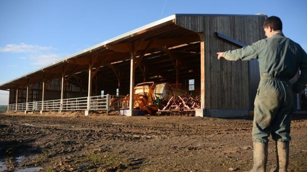 Agriculteur devant un bâtiment